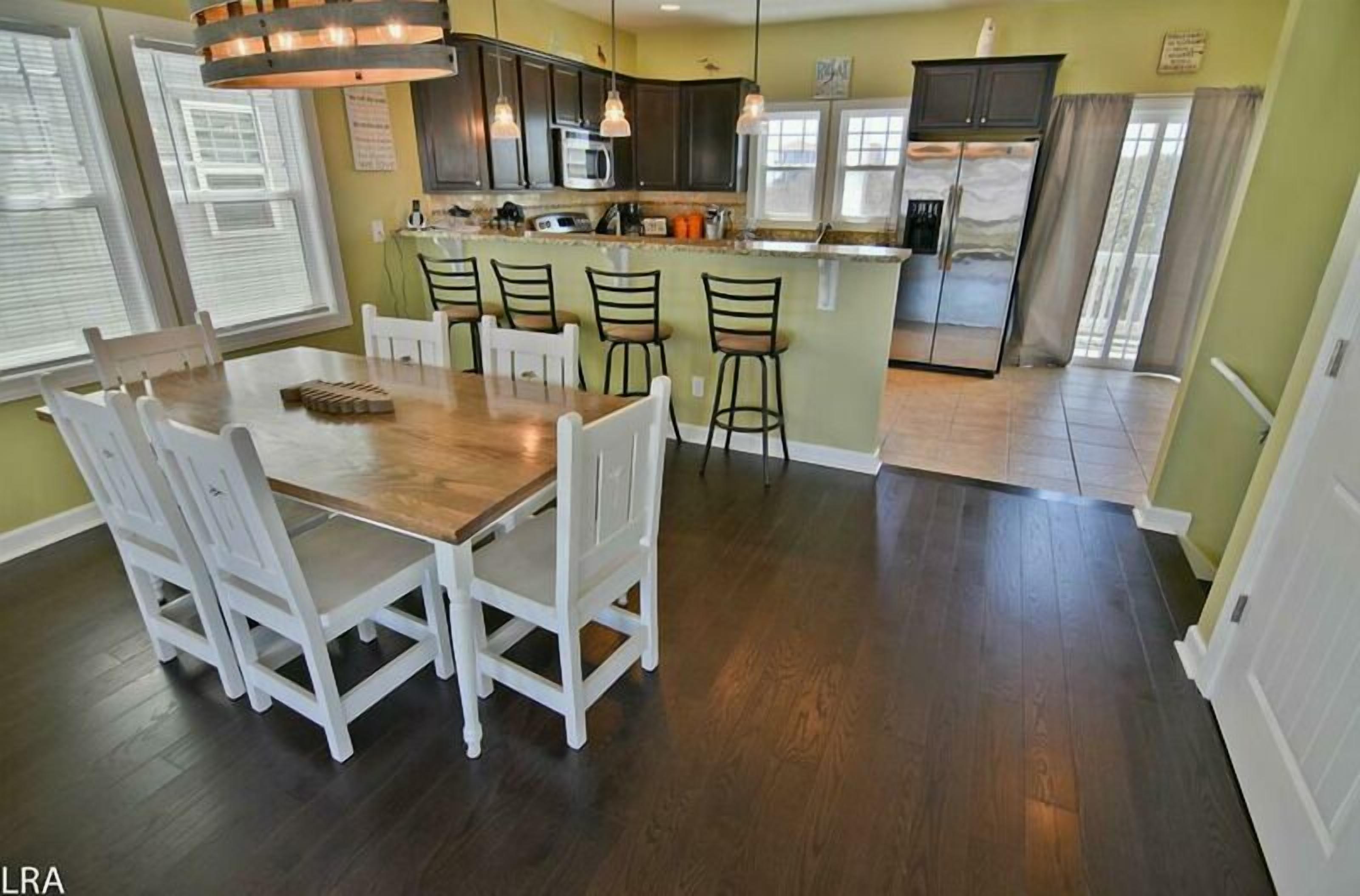 A kitchen with a central island, white chairs, and a dining table.