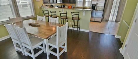 A kitchen with a central island, white chairs, and a dining table.