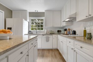 Una cocina moderna con armarios blancos, encimera de granito y ventana que deja entrar luz natural.
