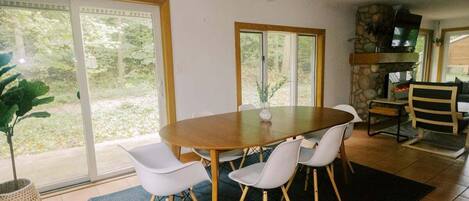 A dining area with a round table, white chairs, and a stone fireplace.
