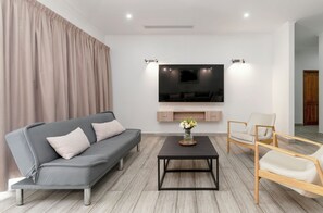A modern living room with a grey sofa, a black coffee table, and a TV mounted on the wall. - Voilà Beau Vallon (Mahé Island)