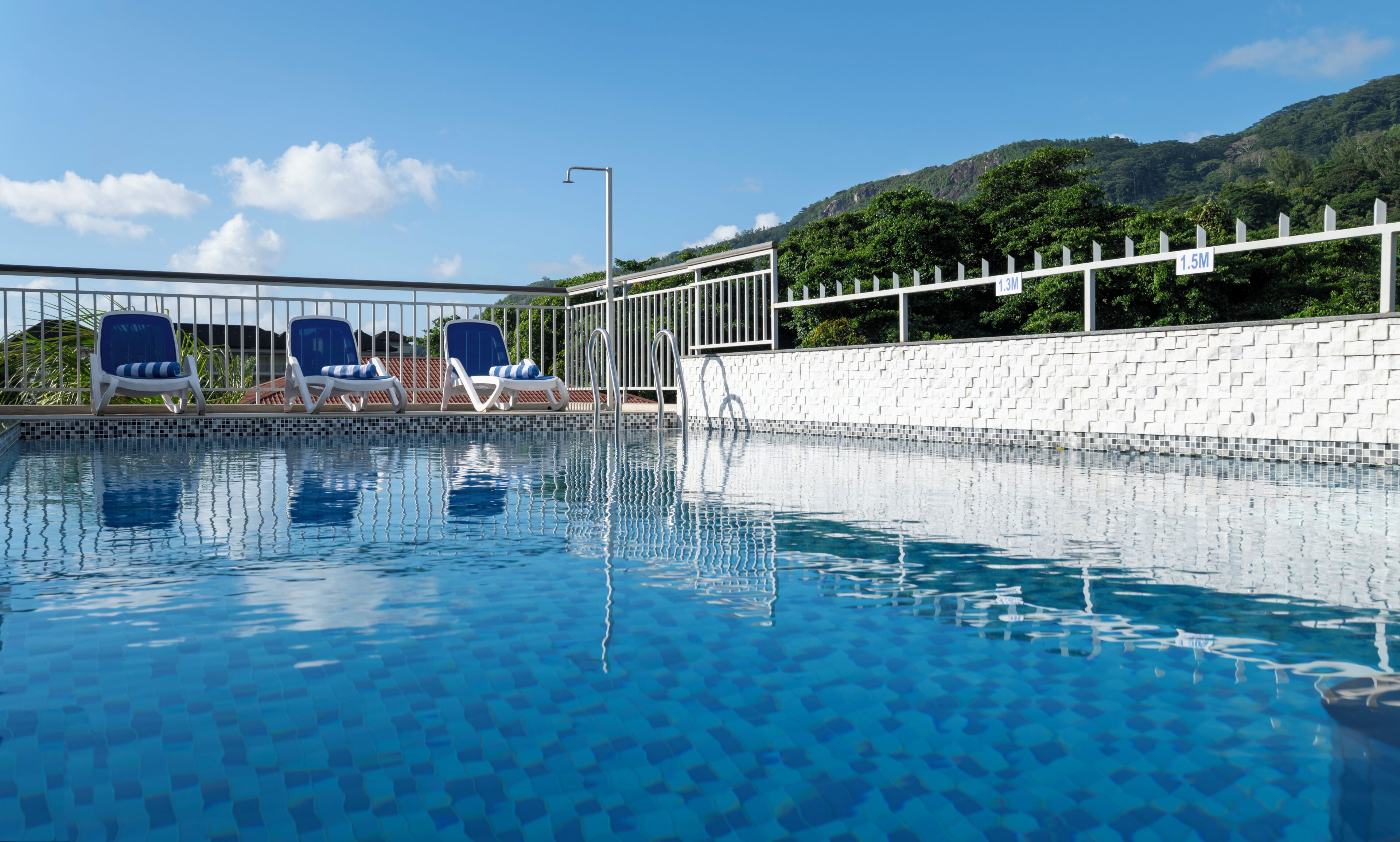 Una piscina al aire libre, sillones reclinables de piscina