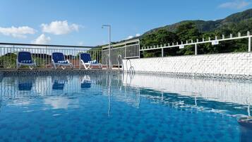 Una piscina al aire libre, sillones reclinables de piscina