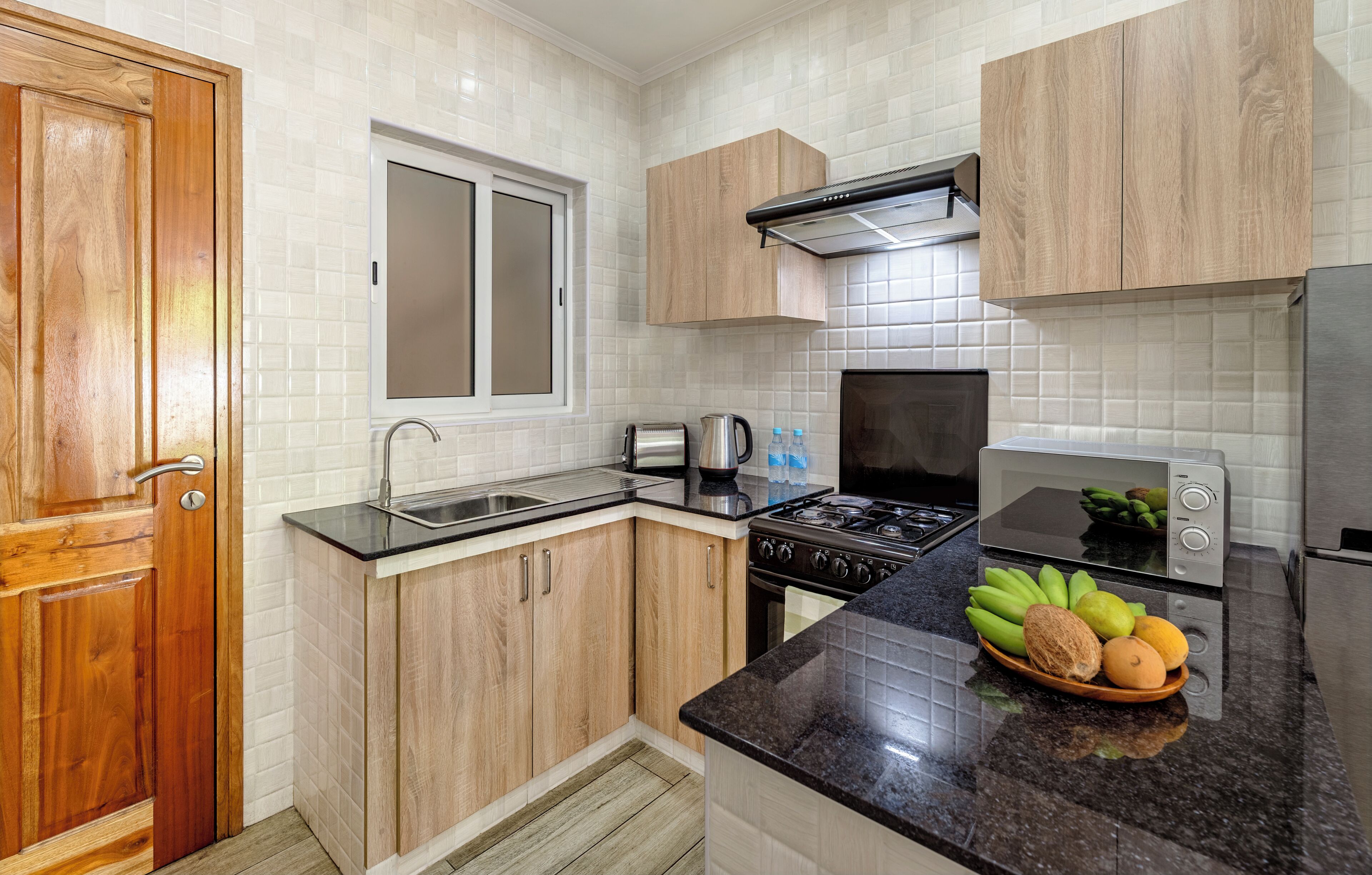 Una cocina con armarios de madera, estufa, pileta y tostadora.