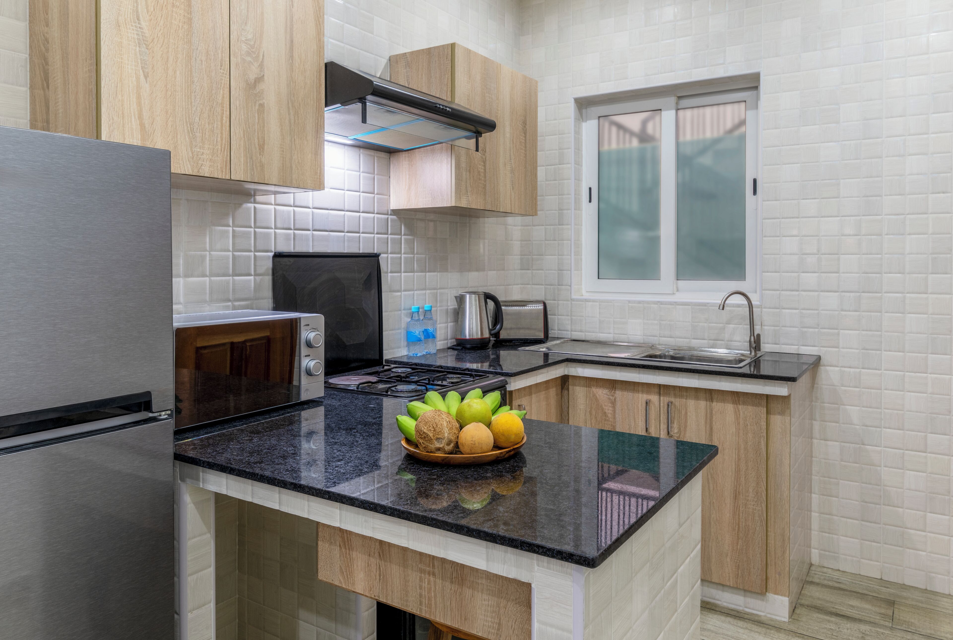 Une cuisine moderne dotée d’appareils électroménagers en acier inoxydable, de meubles en bois et d’un plan de travail en granit noir.
