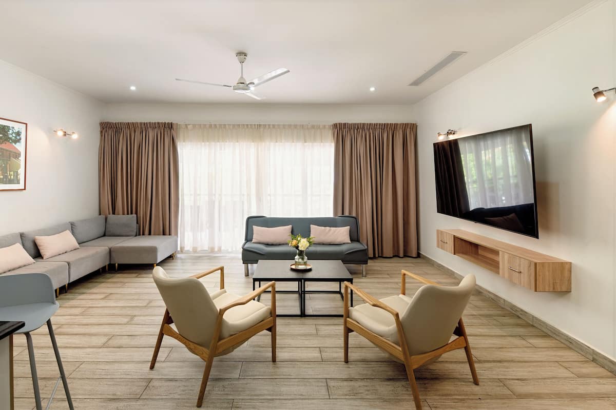 A modern living room with a sectional sofa, a smaller sofa, a coffee table, two chairs, a TV, and a ceiling fan.