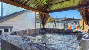 A hot tub with a metal roof and a white picket fence in the background. - The Gather House! Super clean, Super comfortable and Super private! (The Dalles)