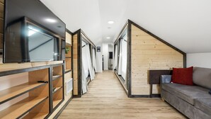 A hallway with a TV, wooden shelves, a sofa, and a wooden wall. - The Gather House! Super clean, Super comfortable and Super private! (The Dalles)