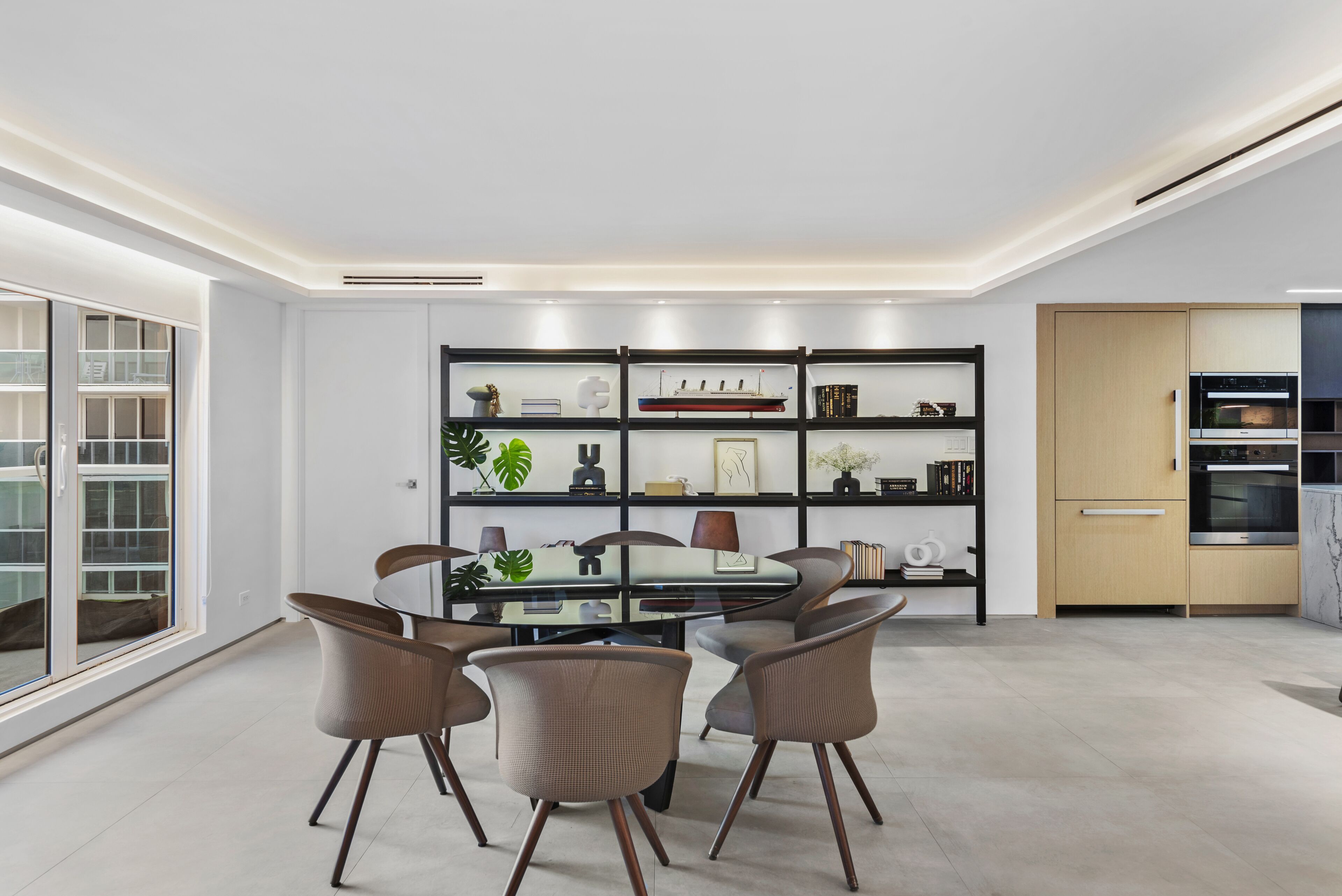 Une cuisine moderne dotée d’appareils électroménagers intégrés, un coin repas avec une table et des chaises en verre, et une grande fenêtre offrant une vue dégagée.