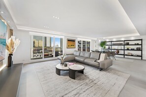 A modern living room with a large sofa, two round coffee tables, and a bookshelf.