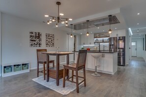 A modern kitchen with stainless steel appliances, wooden chairs, and pendant lighting. - Modern Condo in the Heart of D.C (Washington)