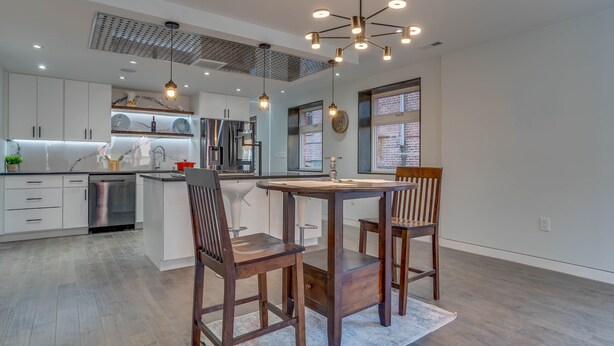 Una cocina moderna con armarios blancos, electrodomésticos de acero inoxidable y una isla central con asientos.