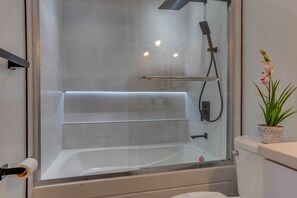 A modern bathroom with a glass-enclosed shower, a toilet, and a potted plant. - Modern Condo in the Heart of D.C (Washington)