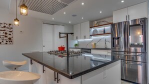 Una cocina moderna con una isla central, electrodomésticos de acero inoxidable e iluminación colgante.