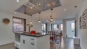 Una cocina moderna con una isla grande, iluminación colgante y vistas al exterior.