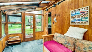 Una habitación acogedora con detalles de madera, un banco cerca de la entrada y un banco acolchado con cojines estampados.