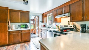 Cocina con armarios de madera, microondas, estufa y cafetera.