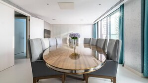 Une salle à manger moderne avec une table ronde, des chaises recouvertes d’un tissu gris et un vase rempli de fleurs.