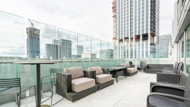 Une terrasse sur le toit, dotée d’un espace extérieur aménagé, d’une rambarde en verre et offrant une vue sur le panorama urbain.