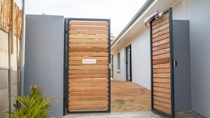 A gated entrance with a 'Welcome' sign, a concrete pathway, and a building in the background. - Casa iLanga guesthouse (Cape Town)