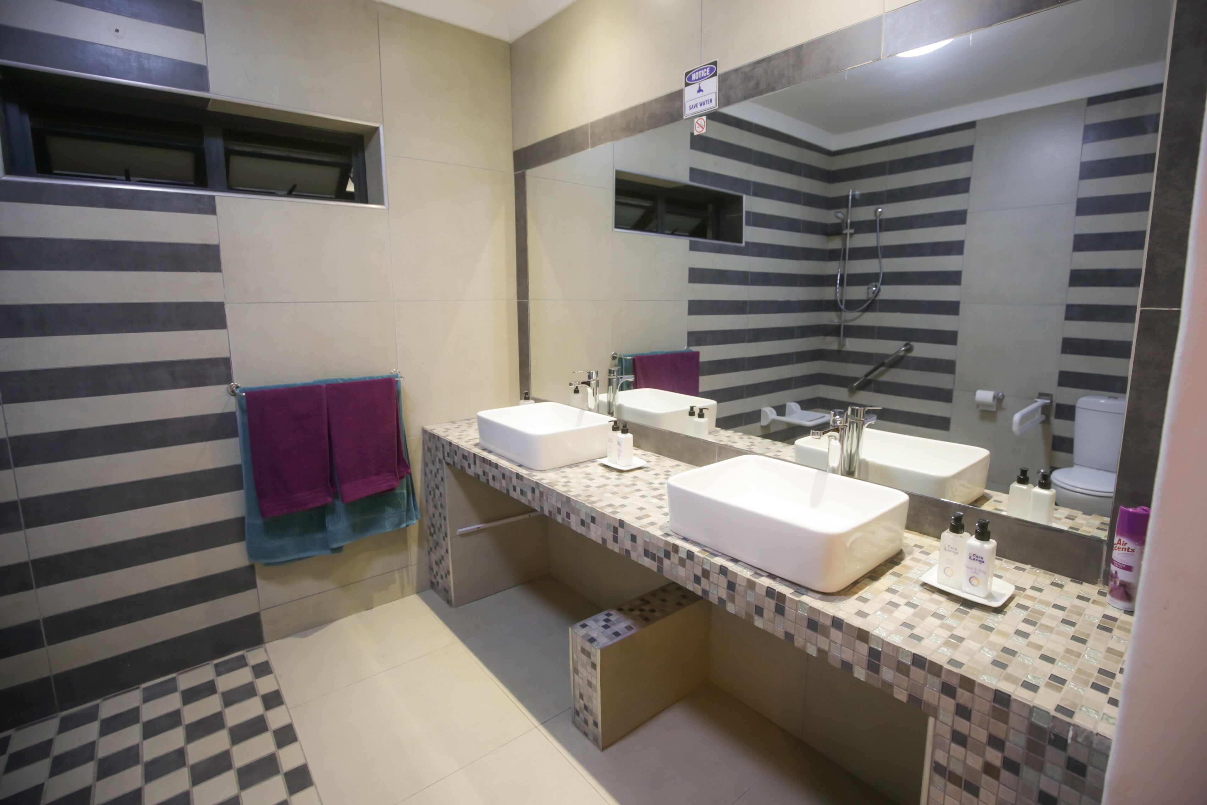 Un baño moderno con dos lavamanos, ducha y un espejo grande.