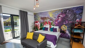 A modern bedroom with a bed, a sofa, and a mural on the wall. - Casa iLanga guesthouse (Cape Town)