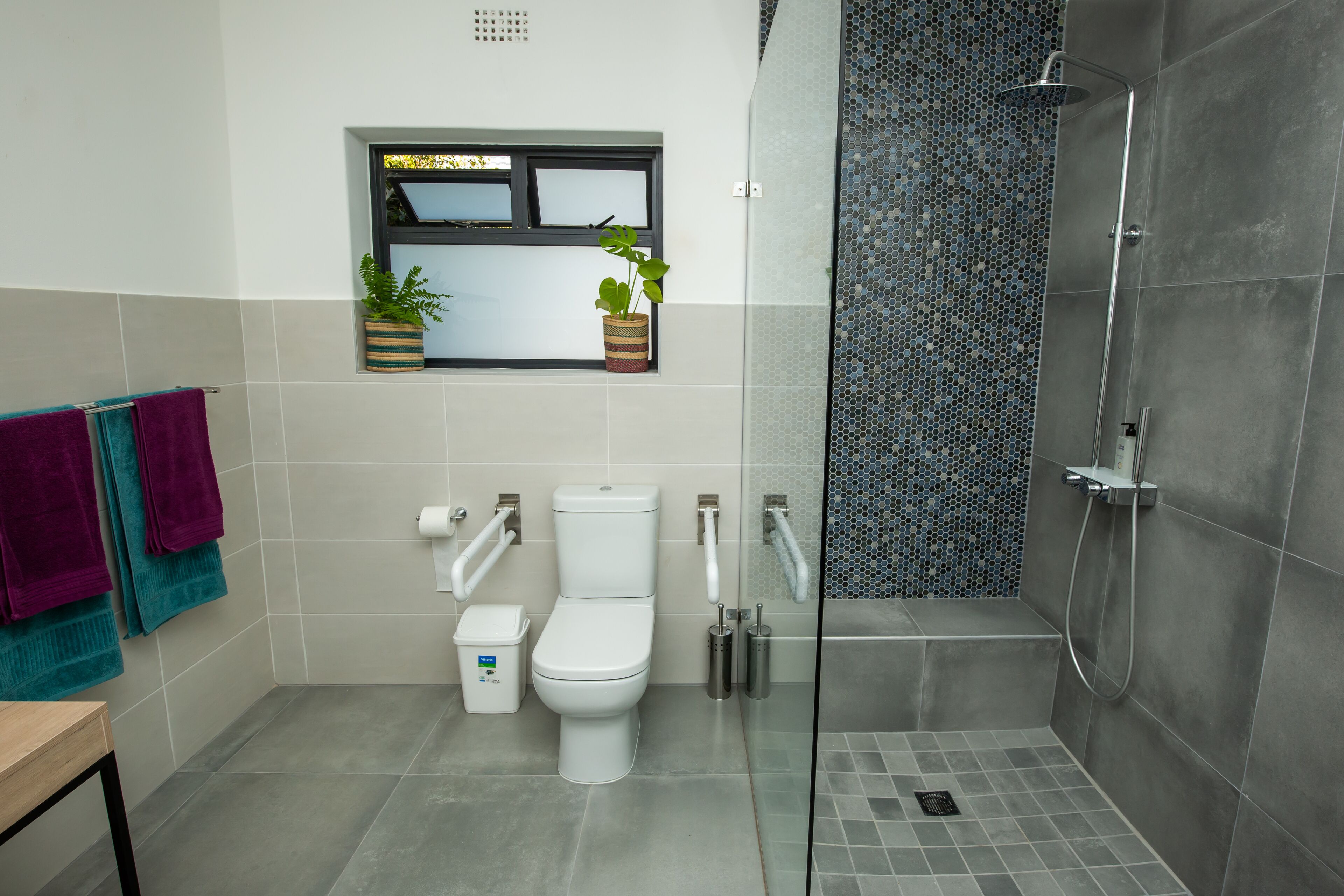 Un baño moderno con inodoro, bidé y ducha con mampara de vidrio.
