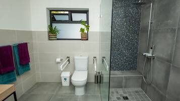 Un baño moderno con inodoro, bidé y ducha con mampara de vidrio.