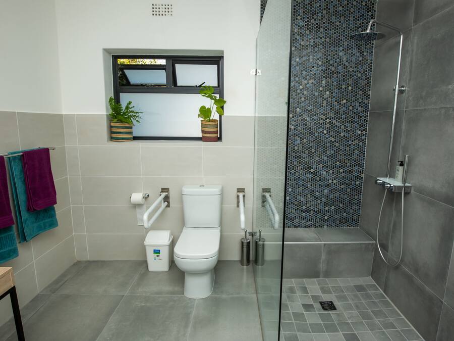 Un baño moderno con inodoro, bidé y ducha con mampara de vidrio.