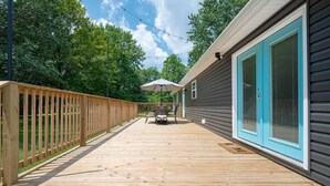 Eine Terrasse mit Holzgeländer, einem Tisch und Stühlen sowie einem Sonnenschirm.