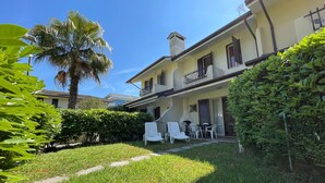 A two-story building with a balcony, outdoor seating, and a well-maintained garden. - Precious Villa With Private Garden and Barbecue (Caorle)
