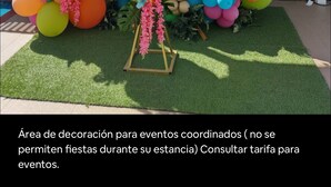 Un espace événementiel décoré, avec un plafond et des murs blancs, agrémenté d’une arche de ballons colorés et d’une table sur laquelle est posé un gâteau.