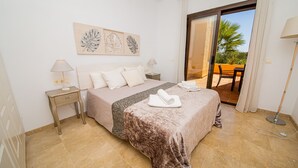 Une chambre d’hôtel avec un lit, deux tables de chevet, une lampe, une serviette, un tableau et une vue sur l’extérieur.