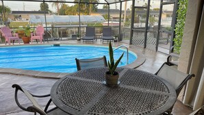 A covered outdoor area with a pool, seating, and potted plants. - Quite Waterfront Villa+Heated Pool+ Close to Dining+Shopping+Entertainment (Cape Coral)