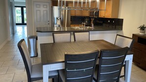 A modern kitchen with a central island, stainless steel appliances, and a pendant light fixture. - Quite Waterfront Villa+Heated Pool+ Close to Dining+Shopping+Entertainment (Cape Coral)