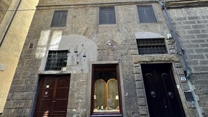 Un bâtiment en pierre à plusieurs étages, doté d’une entrée centrale avec deux grandes portes en bois et une petite fenêtre au-dessus.