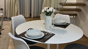 Un coin repas avec une table ronde, des chaises blanches et un vase de fleurs.