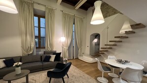 Un salon moderne comprenant un canapé, des fauteuils, une table basse, une table à manger avec des chaises et un escalier.