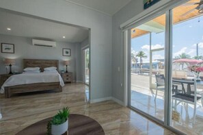 Relax in this serene retreat with a large bed, sliding glass door to an outdoor seating area and a potted plant.