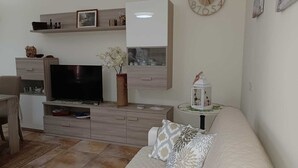 Un salon comprenant un téléviseur, un canapé, une table basse et un vase décoratif.