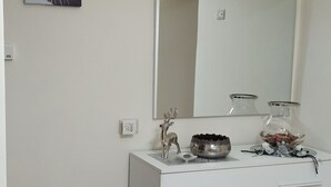 Une salle de bain avec un meuble-lavabo blanc, un miroir et un petit tabouret.