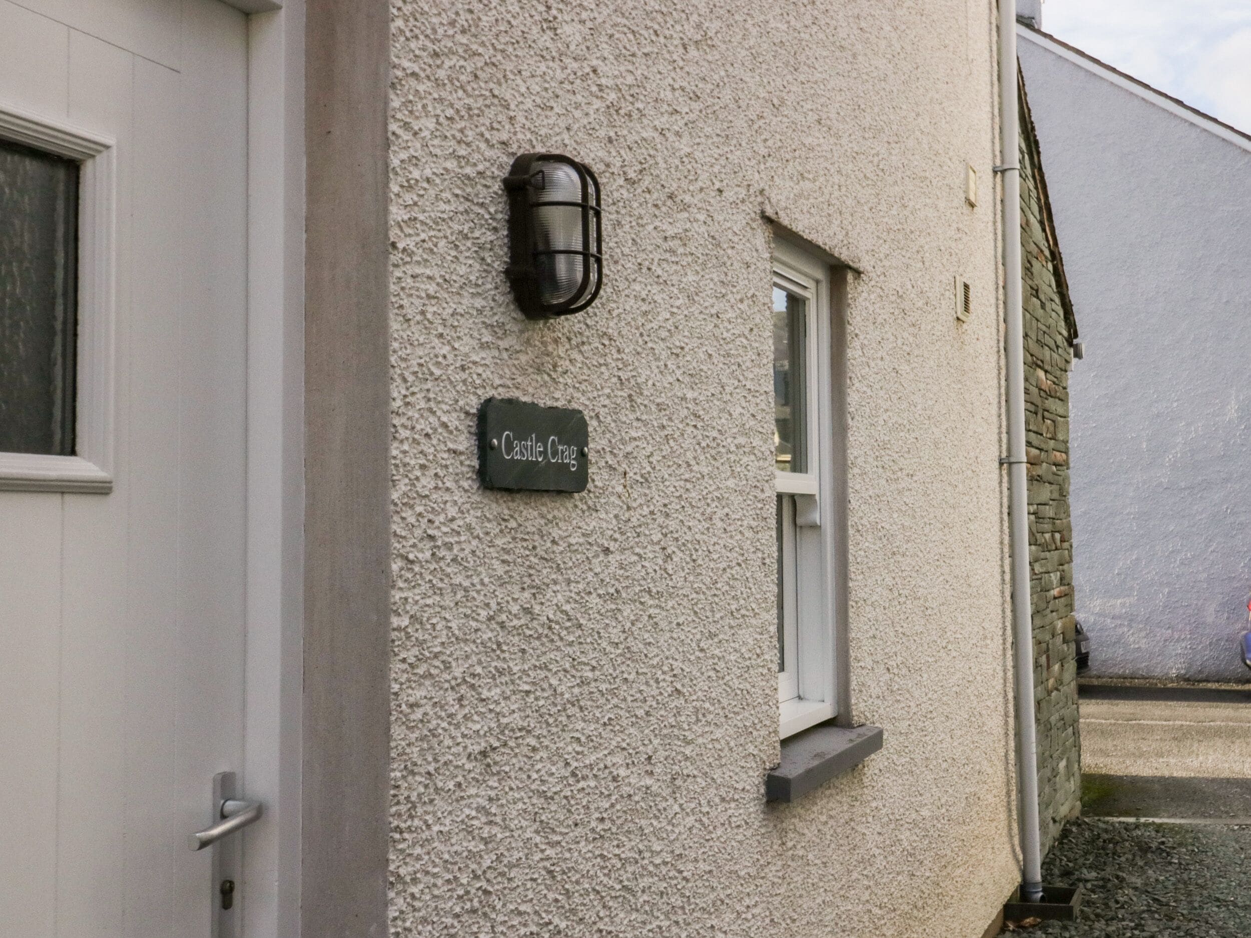 A building with a textured exterior wall, a small window, a door, and a sign reading "Castle Craig."