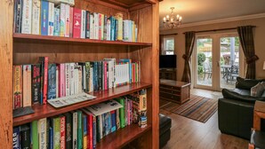 A cozy living room with a wooden bookshelf filled with books, a television, and a comfortable seating area with a sofa and chairs. - Castle Crag (Keswick)
