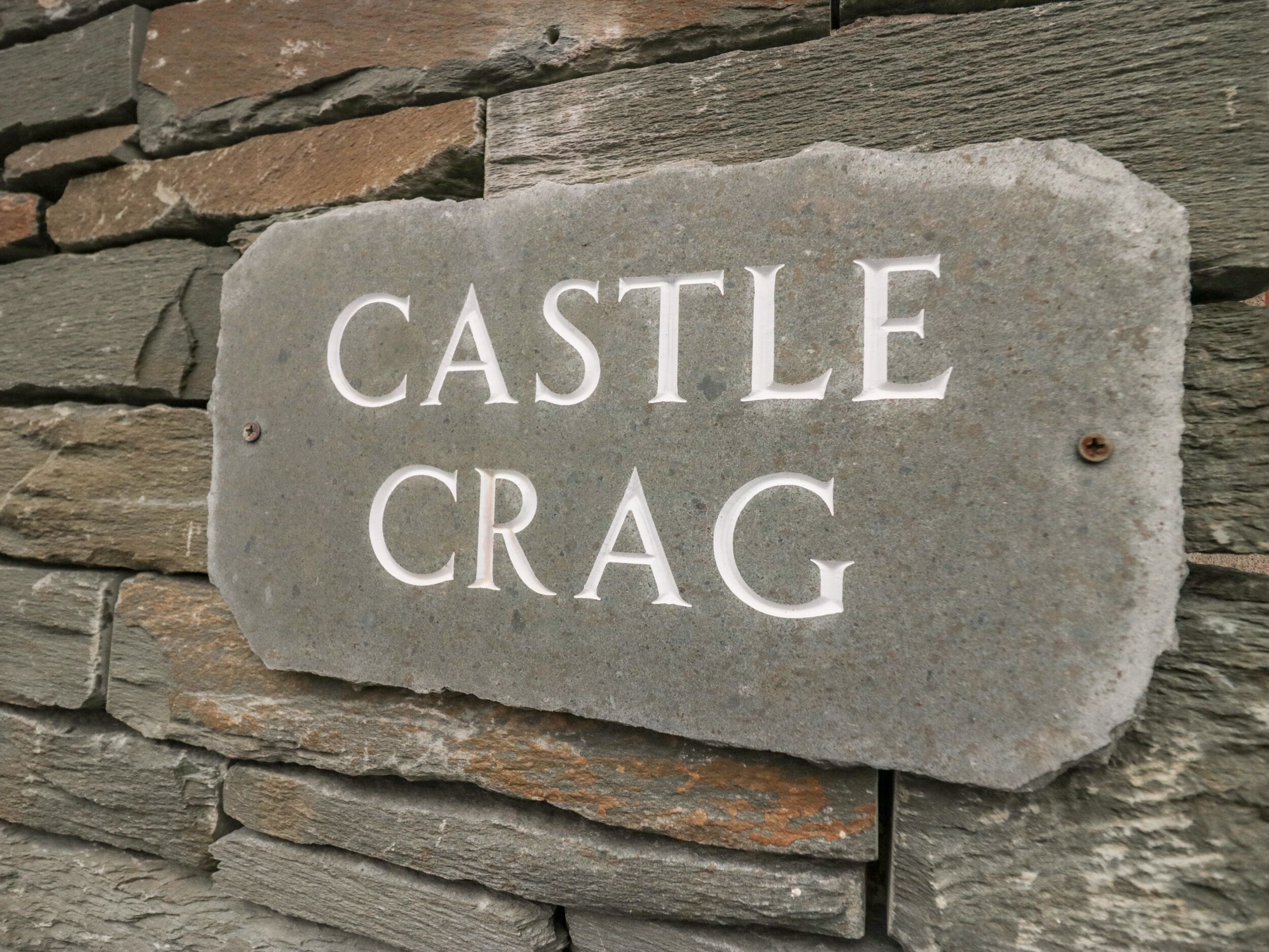 A stone sign with the inscription "CASTLE CRAG" mounted on a stone wall.