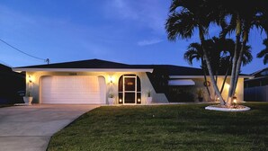 A single-story house with a garage, number 1105, and a well-lit entrance. - Tropical Breeze  Heated Pool, Canal Home, King bed. (Cape Coral)