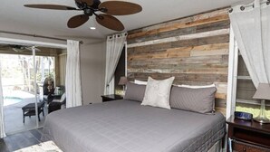 A bedroom with a large bed, a ceiling fan, a wooden headboard, and a view of a patio with outdoor furniture. - Tropical Breeze  Heated Pool, Canal Home, King bed. (Cape Coral)