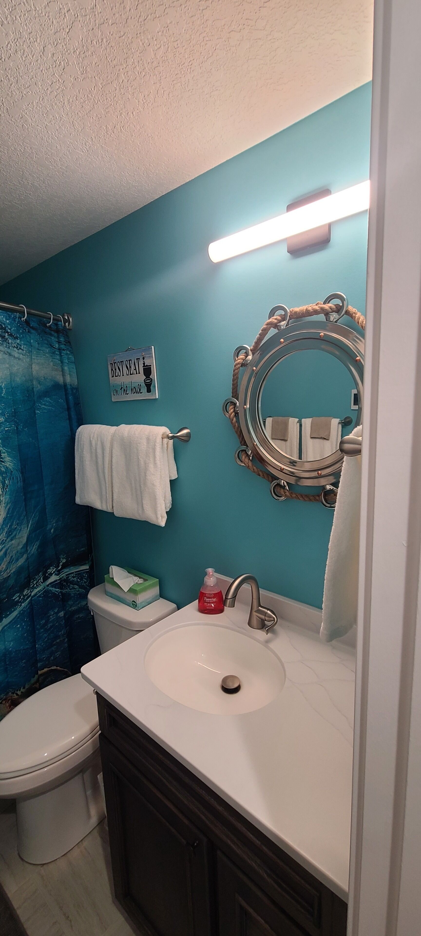 Une salle de bain avec des toilettes, un lavabo et une serviette accrochée au mur.