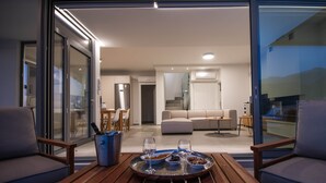 Ein modernes Wohnzimmer mit einem Esstisch für zwei Personen, einer Couch und einer Küche im Hintergrund.