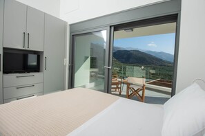 Une chambre avec un lit, une télévision et un balcon équipé d’une table et de chaises.