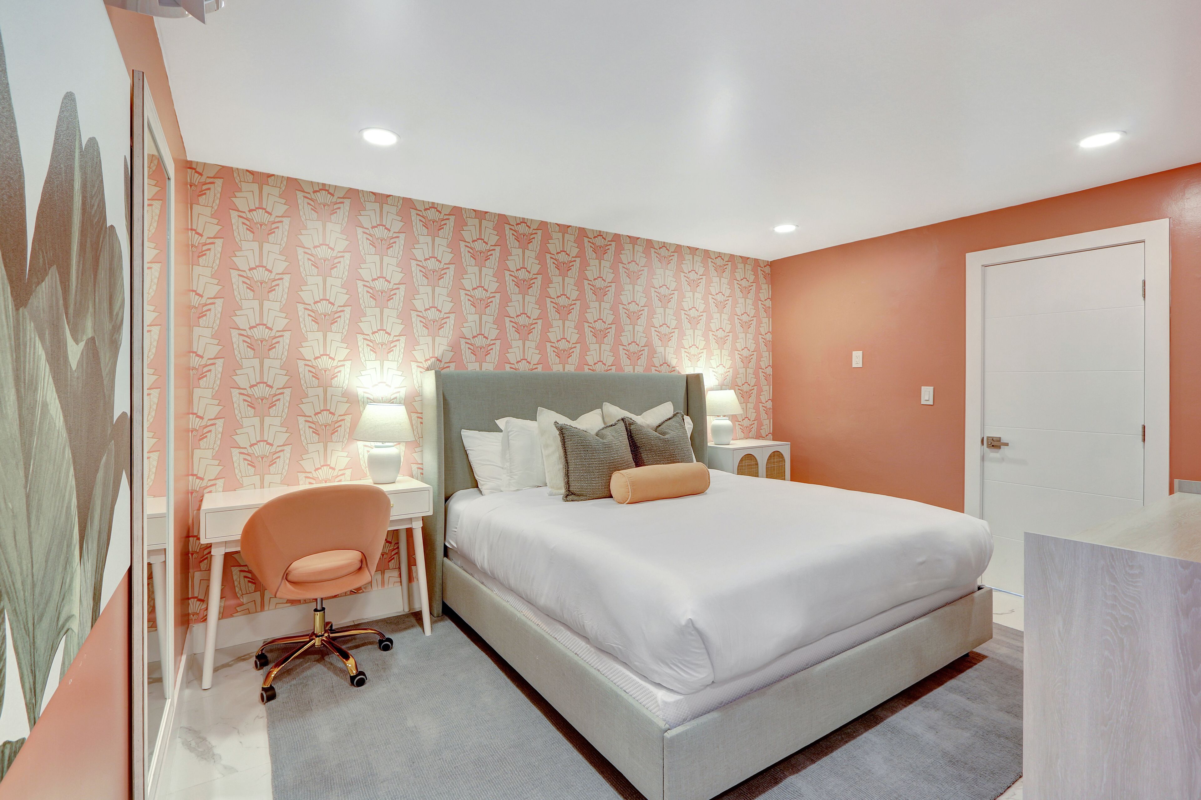 A bedroom with a bed, a desk, a chair, and a nightstand.